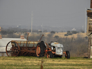 Old Abandoned Farm Tractor with a Faded For Sale Sign on a Hill in the Field