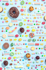 Different types of sweets arranged in a pattern on a blue background. Candy sugar food concept. 