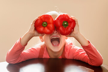 Pepper Sweet California Wonder Bell. Cheerful Child Has Fun Holding pepper in front of eyes, as if in glasses with open mouth. Healthy food for children.