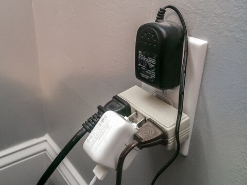 Dangerous overloaded electric outlet with exposed prongs