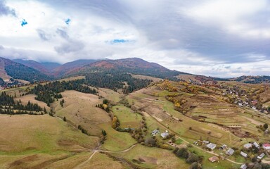 Hill slopes with autumn forests fields and meadows under sky