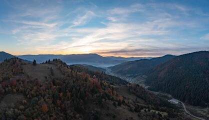 Ground road in high mountains with green forest at sunrise
