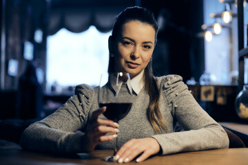 Beautiful girl drinks wine from a glass in a restaurant, a cafe, has a good weekend, a stylish fashionable woman, a brunette young, emotional, outdoor close up.