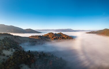 Naklejka na ściany i meble Fog among peaks of high autumn mountains with forests