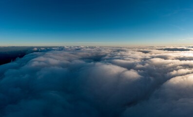 Thick layer of white clouds above mountains at sunrise