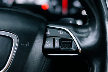 Adaptive cruise control panel buttons on modern car steering wheel, interior details.