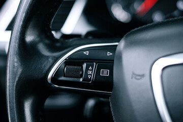 Adaptive cruise control panel buttons on modern car steering wheel, interior details.