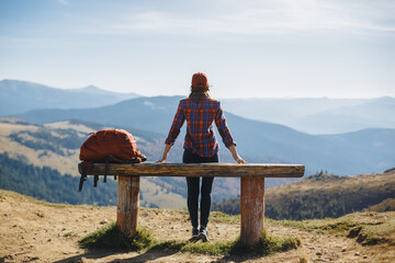 Resting woman hiker sitting enjoying the sun during hiking travel trek. Beautiful young female...