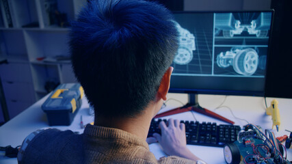 Asian teenager doing Arduino robot homework project in house