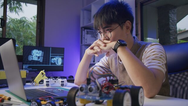 Asian teenager doing Arduino robot homework project in house