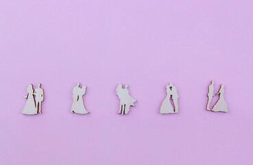 wooden figures in the form of a wedding couple on a pink background