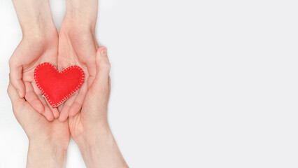 Obraz premium Background banner for Valentine's Day and Mothers Day with a red heart in the hands of a couple on a white background with copy space