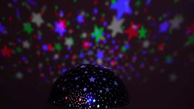 kids projector reflects moving colorful stars on the wall creating psychedelic night sky effect - colorful night background with stars in the sky - disco light 