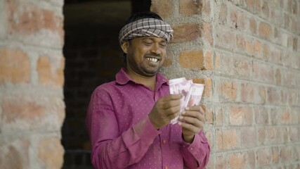 happy young indian daily wager or construcation worker counting money at workplace - concept of blue collar job earnings,banking and financial.