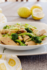 Pasta with broccoli, chickpeas and lemon zest. Vegan recipe. Lemons in the background