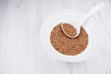 buckwheat in a white bowl with a spoon on the table