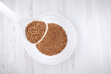 buckwheat in a white spoon. Spoon with buckwheat on the background of a plate with buckwheat