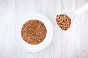 buckwheat in a white spoon. Spoon with buckwheat on the background of a plate with buckwheat