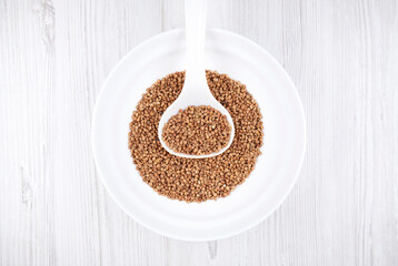 buckwheat in a white bowl with a spoon on the table