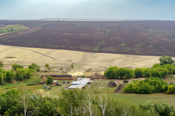 Rural landscape at the end of summer, with an agricultural farm and a plowed field. Russia, Orenburg region, farm Arapovka