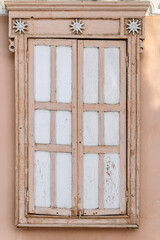 Old wooden window with closed shutters and cracked paint. Russia, city of Orenburg