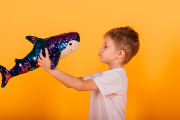 Child boy in yellow studio with toys fish shark toy