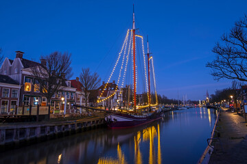 Decorated traditional sailing ship in the harbor from Harlingen in the Netherlands at sunset