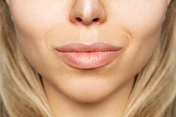 Cropped shot of young caucasian blonde woman's face with perfect lips after lip enhancement. Injection of filler in lips. Lip augmentation. Close up