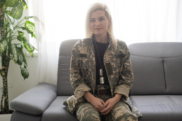 close-up portrait of thoughtful female soldier in military uniform with ptsd sitting on couch and...
