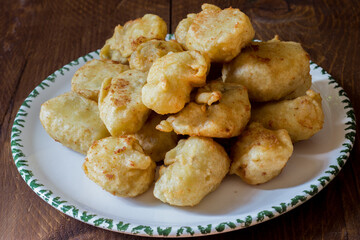 Fried cod served in serving dish on wooden background