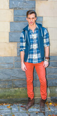 Dressing in a sleeveless hoodie, a long sleeve, patterned shirt, red pants, brown boots, one young...