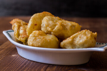 Fried cod served in serving dish on wooden background