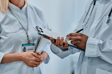 Cropped image of two doctors writing information on forms. Background.