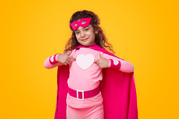 Smiling girl in superhero costume with heart