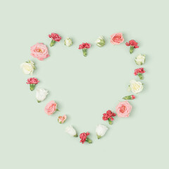 Various colorful spring flowers heart layout on a light green background. Valentine's day minimal...