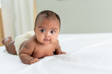 African baby black skin newborn is  3 month old, lying on white bed  in a bedroom,  to African...