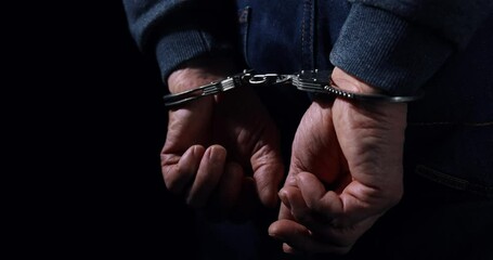 arrested man with cuffed hands behind back - Powered by Adobe