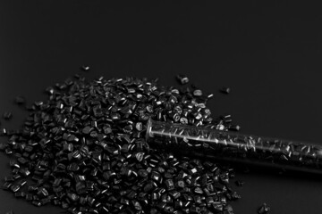 Many black granules of polypropylene, polyamide in a test tube. Background. Plastic and polymer industry, industry. Microplastic products.