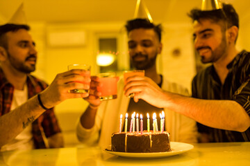 Excited arabian man ready to blow out candles on cake on birthday party with happy friends in the house