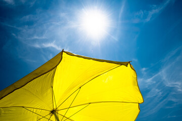 Yellow Umbrella with Bright Sun and Blue Sky