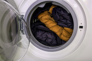 Dirty clothes of different colors in a washing machine drum, laundry concept