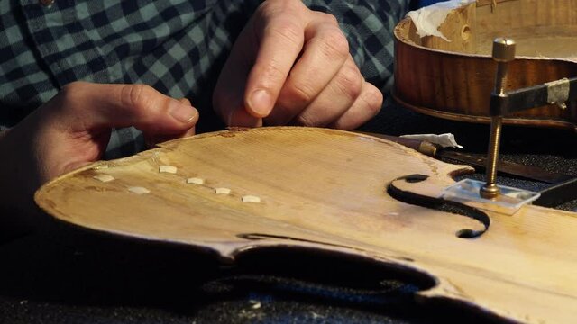 luthier artisan restoring an old italian classic handmade violin in his workshop - specialized craftmanship concept