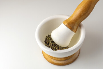 Spices in a mortar and pestle. Dried herbs in a white ceramic mortar on a white background....
