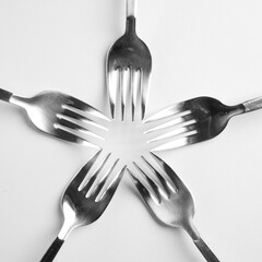 five gray metal forks make together an abstrakt flower