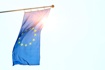 EU flag of European Union with sunbeam against blue sky, space for text