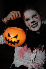 A vertical shot of a terrifying young girl in a bloody mime costume posing scarily at the camera