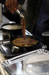 chef en cocina preparando plato de anchoas caseras en salazón dentro de una cazuela