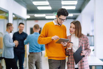 Colleagues with coffee are discussing a new business project in the creative office.Group of young...