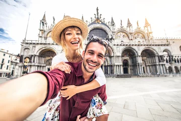 Poster Beautiful young couple having fun visiting Venice - Tourists enjoying holiday in Italy taking selfie in front of famous landmark - Vacation and happy lifestyle concept © Davide Angelini