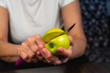 An apple and a knife in the hands of a woman.